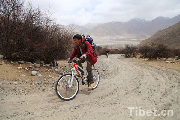 The BMX amateur rides the bicycle difficultly upward on the slope. [Photo/China Tibet Online]