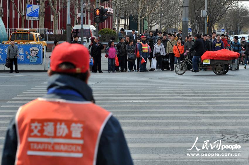With the instruction of a traffic warden, pedestrians cross the road in an orderly manner at a crossing of Da Wang Road on April 9,2013.(People's Daily Online/Weng Qiyu)