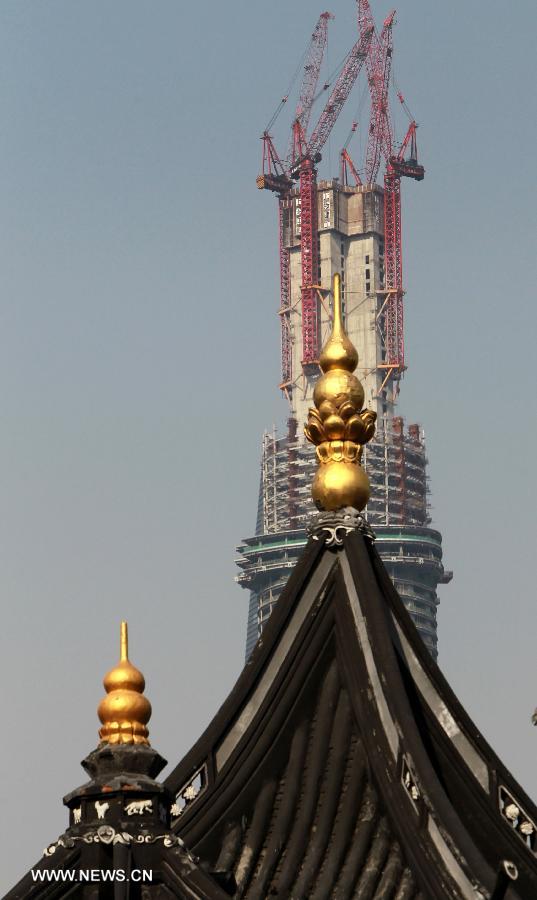 Photo taken on April 11, 2013 shows the Shanghai Tower with the tops of traditonal buildings in the foreground, in east China's Shanghai Municipality. The height of the Shanghai Tower, which is still under construction, reached 501.3 meters Thursday, surpassing the neighbouring Jinmao Tower and the World Financial Center. The designed height of the Shanghai Tower will be 632 meters, the tallest skyscraper in China. (Xinhua/Pei Xin) 