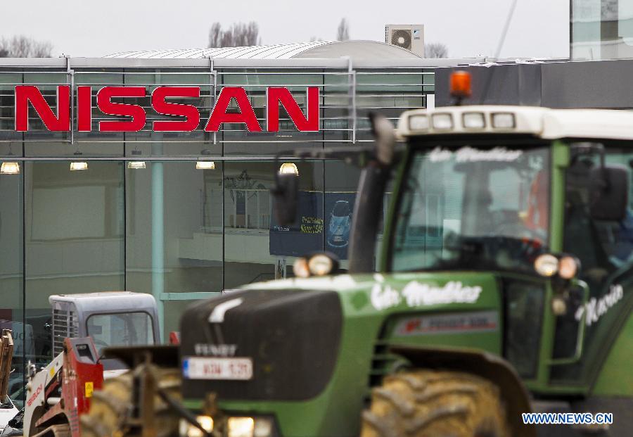 A tractor passes a sales office of Japanese auto producer Nissan in Brussels, capital of Belgium, April 11, 2013. Four Japanese auto giants (Toyota, Nissan, Honda and Mazda) said Thursday they are recalling nearly 2.92 million vehicles worldwide because of airbag problems.(Xinhua/Zhou Lei) 