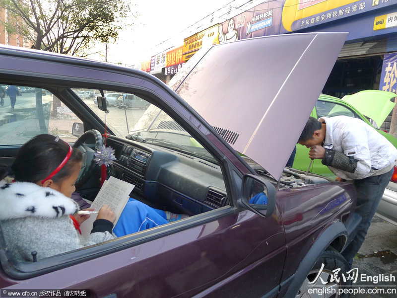 A pupil sitting in the car seizes every minute to do her homework. (Photo by Li Wenming/ CFP)