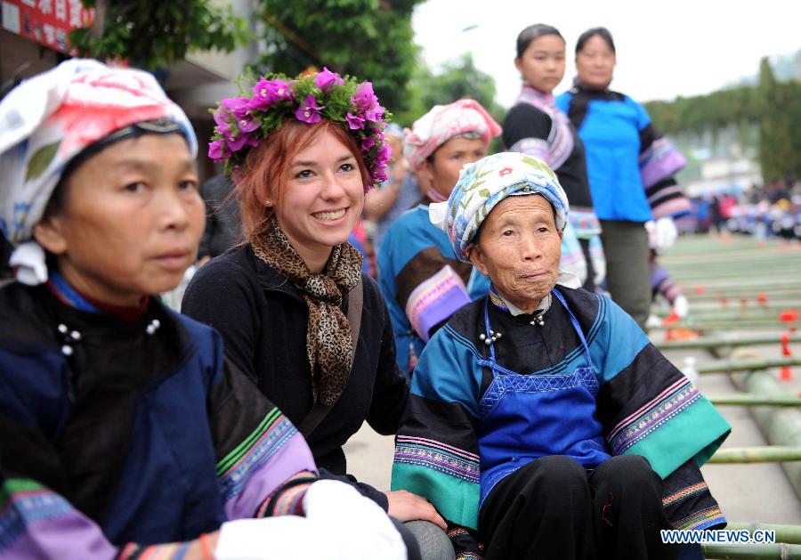A French woman (C, front) poses for group photos with women of Dai ethnic group during a folk custom and culture festival marking the "San Yue San" (the third day of the third lunar month in Chinese Calendar) in Shizong County, southwest China's Yunnan Province, April 12, 2013. The festival, attracting tens of thousands of local residents and tourists from both at home and abroad, was held here Friday. (Xinhua/Yang Zongyou)