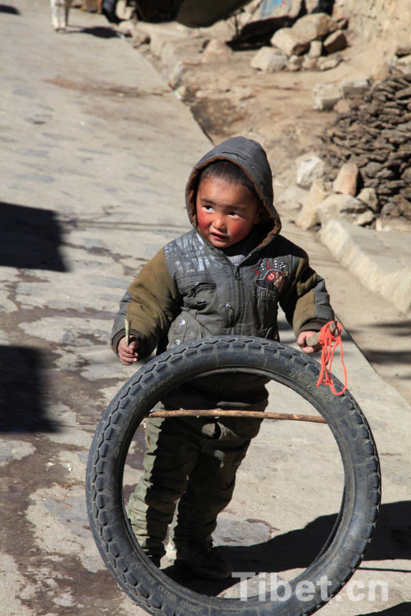 A Tibetan kid plays with a "tyre toy" in Lhoka Prefecture, southern Tibet. Lhoka, a glorious place with remarkable people, is the cradle of Tibetan civilization. [Photo/China Tibet Online]