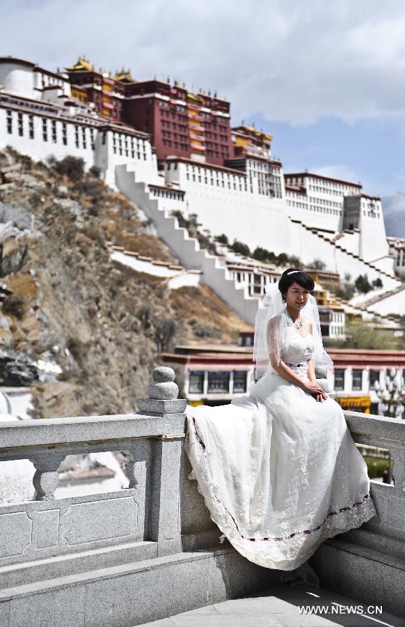 A young woman poses for wedding photo in front of the Potala Palace in Lhasa, capital of southwest China's Tibet Autonomous Region, April 7, 2013. [Photo/Xinhua]