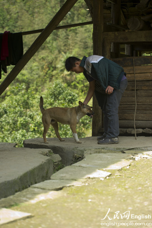 Yu Qiyun greets his dog outside his house, Sangzhi county, Hunan province April 11, 2013. (Photo/ People's Daily Online)