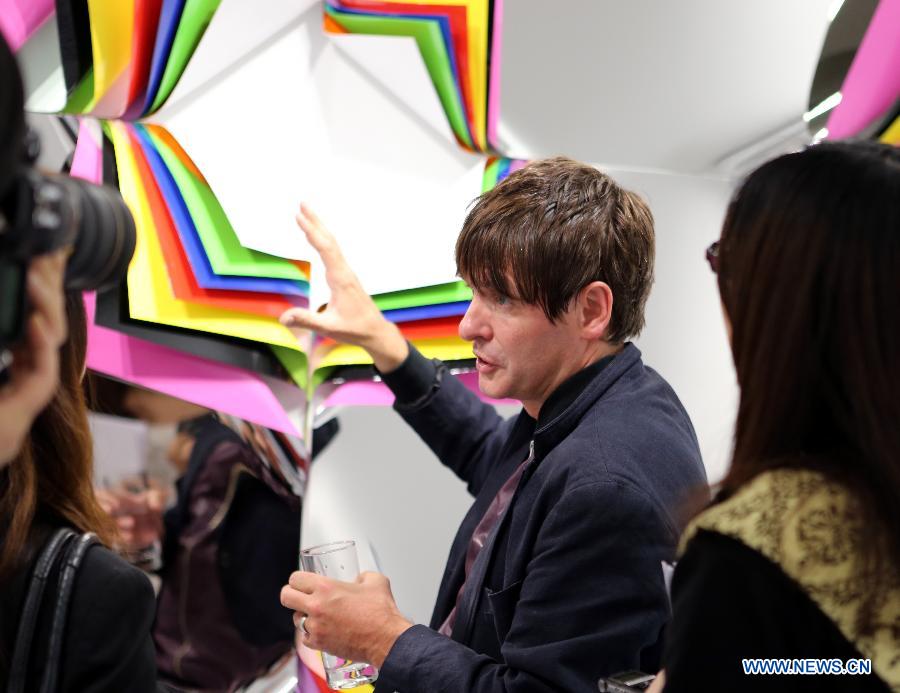 British visual artist Jim Lambie (C) introduces a piece of work to visitors at his "Flowers of Romance" Installation Art Exhibition in Hong Kong, south China, April 16, 2013. (Xinhua/Li Peng) 