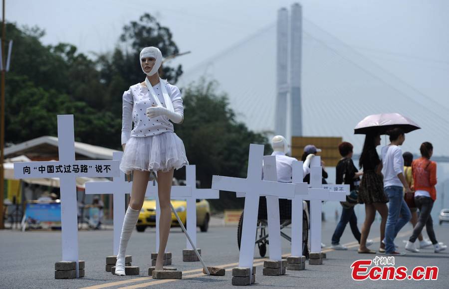Crosses with words "say no to Chinese-style street crossing" are erected around two mannequins bound by bandage in street of downtown Chongqing, April 16, 2013. The installation warned people to obey traffic regulations. (CNS/Chen Chao)