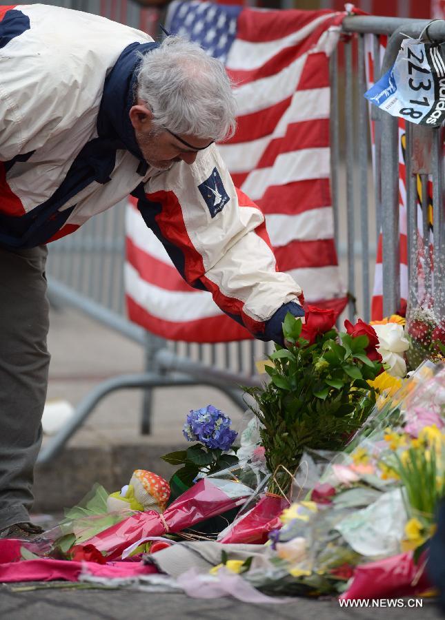 A citizen offers flowers for the victims in Boston Marathon blasts in Boston, the United States, April 16, 2013. The death toll has risen to three, with 176 people injured. (Xinhua/Wang Lei) 