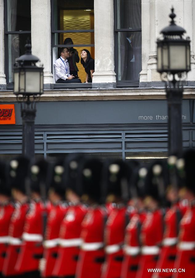 Office workers look on the ceremonial funeral of the former Prime Minister Baroness Thatcher through a window of a building near St. Paul's Cathedral in London, Britain, April 17, 2013. The funeral of Margaret Thatcher, the first female British prime minister, started 11 a.m. local time on Wednesday in London. (Xinhua/Wang Lili)