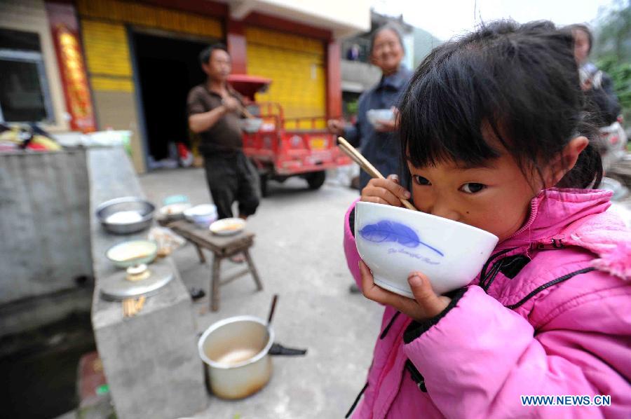 A little girl eats outside in quake-hit Qingren Township, Lushan County, Ya'an City, southwest China's Sichuan Province, April 20, 2013. (Xinhua/Yu Ping)