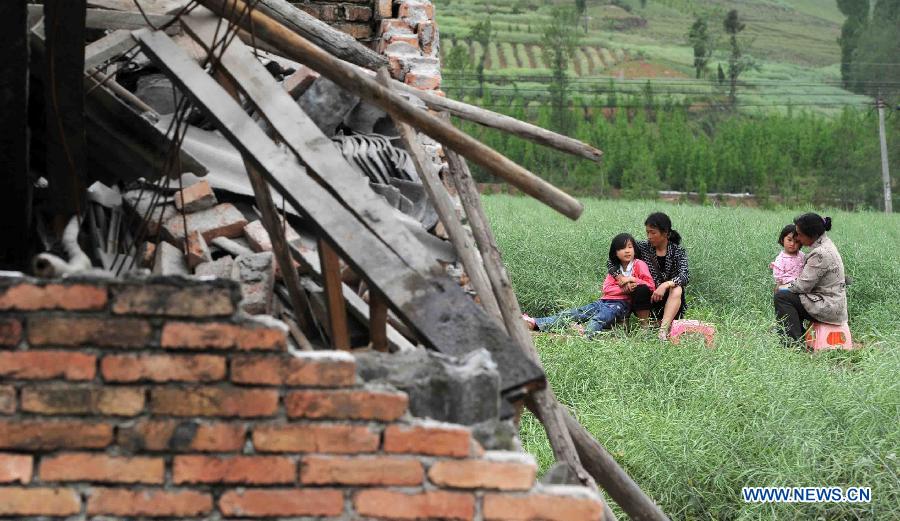 Local residents rest near destroyed houses in quake-hit Qingren Township, Lushan County, Ya'an City, southwest China's Sichuan Province, April 20, 2013.  (Xinhua/Yu Ping)