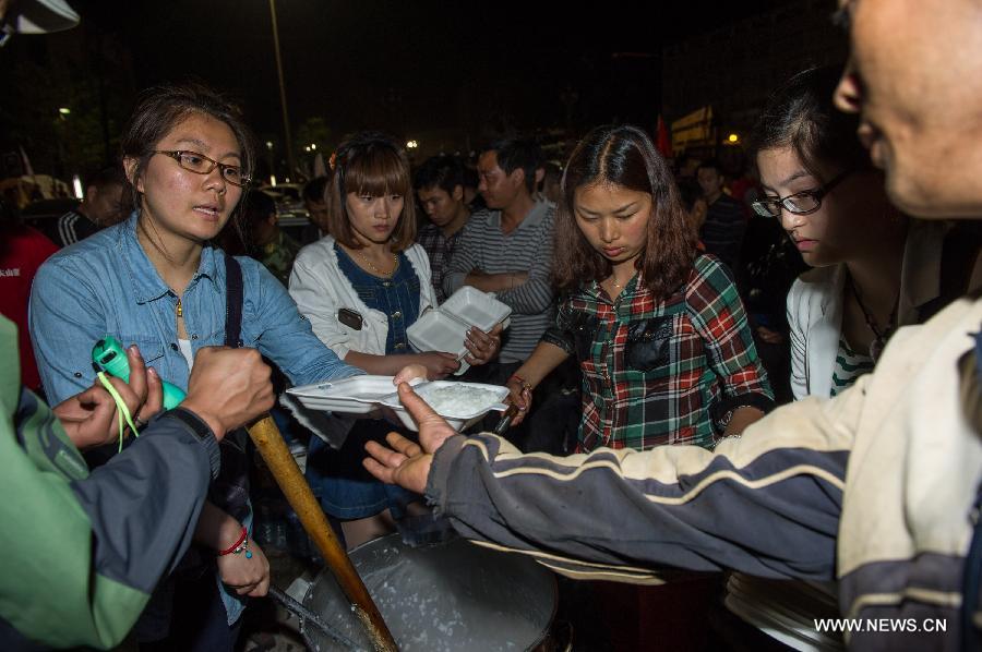 Volunteers offer hot porridge to quake victims at the Lushan Stadium, a temporary shelter site, on the first night after the deadly earthquake in Lushan County in Ya'an City, southwest China's Sichuan Province, April 21, 2013. A 7.0-magnitude earthquake jolted Lushan County of Ya'an City on April 20 morning. Many citizens chose to spend the first night after the quake on roads or in temporary tents. (Xinhua/Chen Cheng) 