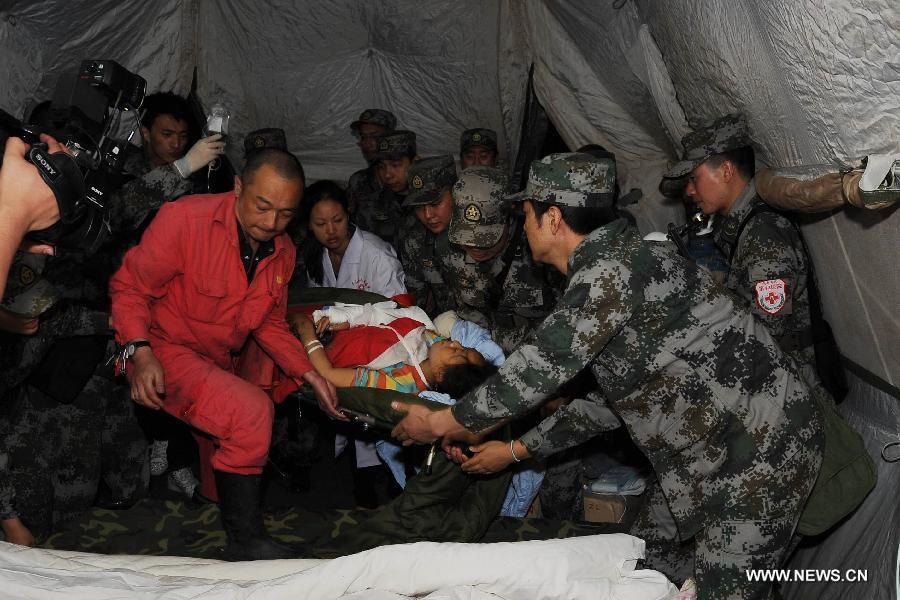 Doctors from the Chengdu Military Region treat a victim from Lingguan Township of the badly-hit Baoxing County in a temporary tent outside the Lushan People's Hospital in Lushan County of Ya'an City, southwest China's Sichuan Province, April 21, 2013. A 7.0-magnitude earthquake which hit Lushan County on April 20 morning damaged the Lushan People's Hospital and doctors had to erect temporary tents outside the hosptial to treat the injured people. (Xinhua/Li Jian) 