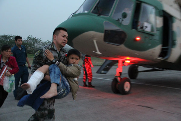 A military officer carries an injured boy from a helicopter for medical treatment at an airport in Chengdu city, Southwest China's Sichuan province, on April 20, 2013. (Photo/Xinhua)