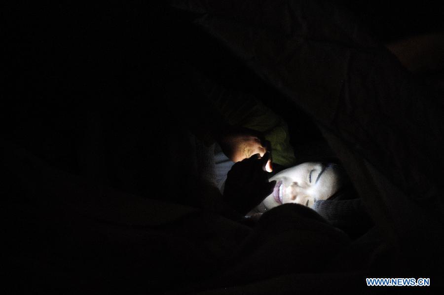 A citizen plays with a mobile phone in a temporary tent on the second night after the deadly earthquake in Lushan County in Ya'an City, southwest China's Sichuan Province, April 21, 2013. A 7.0-magnitude earthquake jolted Lushan County of Ya'an City on April 20 morning. (Xinhua/Wen Tao) 