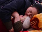 A mother holds her kid and falls asleep in a shelter in quake area 