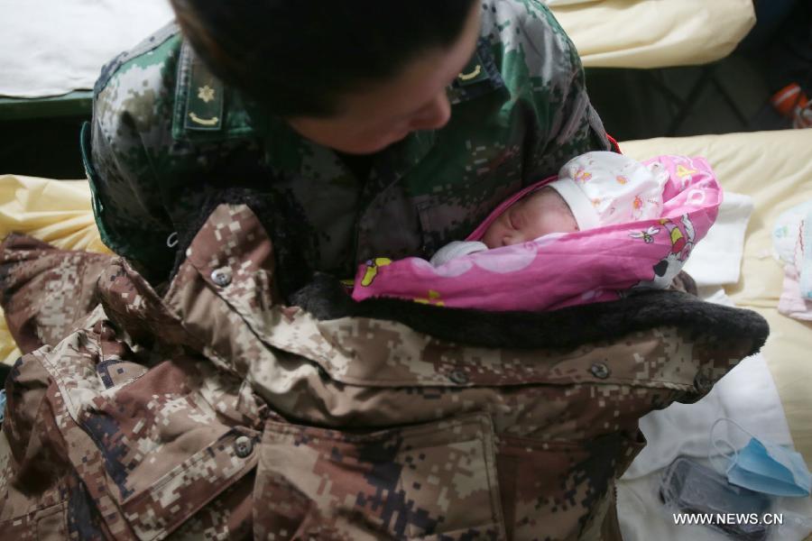 A medical worker holds the newborn child Zhang An in her arms to keep the baby warm in the quake-hit Lushan County, southwest China's Sichuan Province, April 22, 2013. Liu Li, a villager of Luyang Township of Lushan County, gave birth to the baby girl Zhang An on Monday night. A 7.0-magnitude earthquake jolted Lushan County on April 20, leaving at least 192 people dead and 23 missing. More than 11,000 people were injured. (Xinhua/Jin Liwang) 