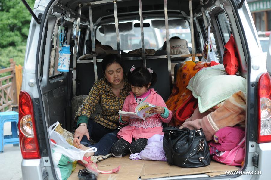 Xian Yuqin (R), reviews her lessons in a vehicle of her family in quake-hit Baoxing County of Ya'an City, southwest China's Sichuan Province, April 23, 2013. Xian's whole family lived in the vehicle these days after a 7.0-magnitude earthquake jolted Lushan County of Ya'an City on April 20. (Xinhua/Luo Xiaoguang)  