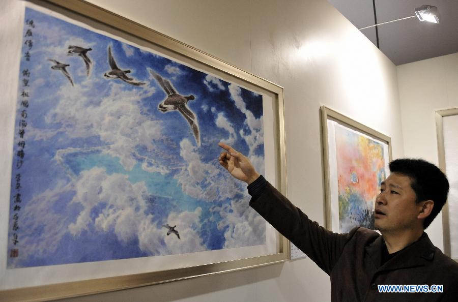 Painter Li Dong introduces his painting at an art exhibition themed on Chinese ocean in Beijing, capital of China, April 24, 2013. Over 130 pieces of artworks are on display. (Xinhua/Li Xin)