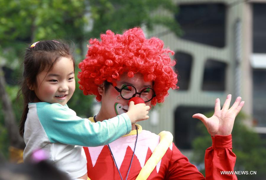 A performer dressed as a clown poses for photo with a girl during a cartoon and animation floats parade, part of the ninth China International Cartoon & Animation Festival, in Hangzhou, capital of east China's Zhejiang Province, April 28, 2013. (Xinhua/Wu Huang)