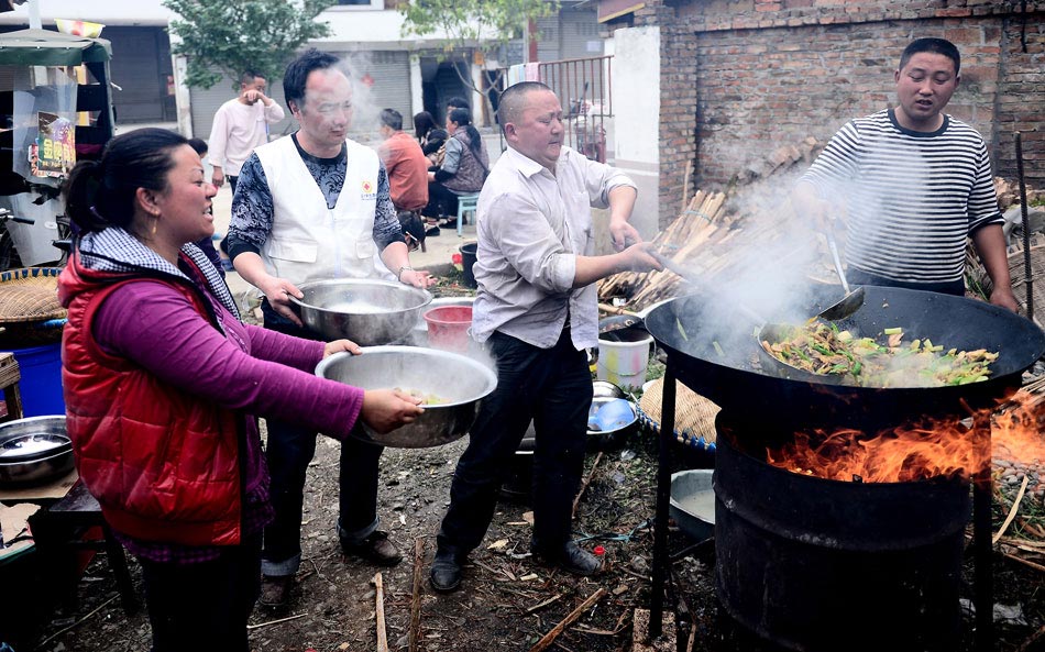 Li Haizheng (right) cooks in the open air on April 22, with a big iron pot which he risked life to pick from his tumbledown house after a 7.0-magnitude earthquake shook Sichuan’s Lushan County. The courtyard of Li’s home has become a temporary canteen to serve hot and tasty meals for his quake-affected neighbors. (Xinhua/Zhang Hongxiang)