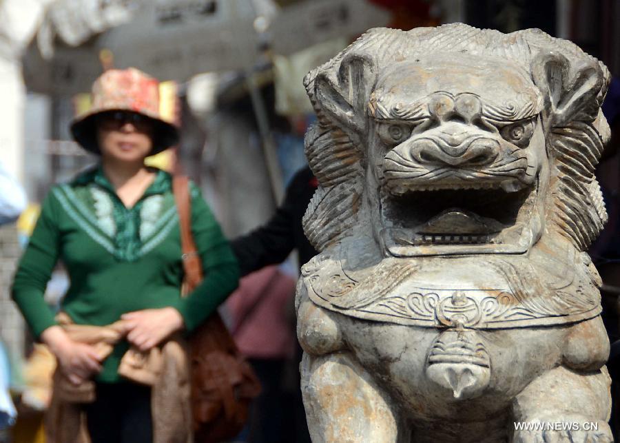 A tourist walks towards a stone lion in Sanhe Town of Feixi County, east China's Anhui Province, April 25, 2013. The Sanhe Ancient Town, which has a history of more than 2,500 years, is a typical "ancient town full of rivers and lakes, together with small bridges, flowing water and local dwellings." (Xinhua/Wang Song)
