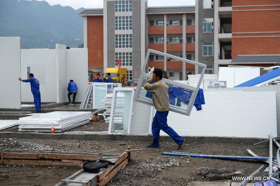 Workers build prefabricated houses on the play ground of the middle school of Taiping Village in Lushan County of Ya'an City, southwest China's Sichuan Province, April 30, 2013. The earthquake hitting Lushan on April 20 has damaged the buildings of 357 schools in Ya'an, disturbing the teaching activities in 329 middle and primary schools. Local people built prefabricated houses for the school children to continue their lessons in recent days. (Xinhua/Jin Liangkuai)