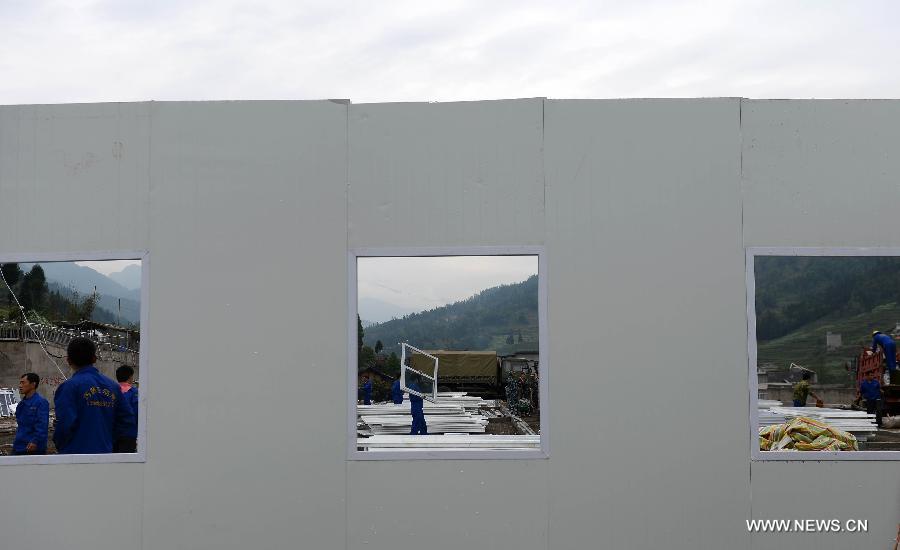 Prefabricated houses under construction are seen on the play ground of the middle school of Taiping Village in Lushan County of Ya'an City, southwest China's Sichuan Province, April 30, 2013. The earthquake hitting Lushan on April 20 has damaged the buildings of 357 schools in Ya'an, disturbing the teaching activities in 329 middle and primary schools. Local people built prefabricated houses for the school children to continue their lessons in recent days. (Xinhua/Jin Liangkuai)