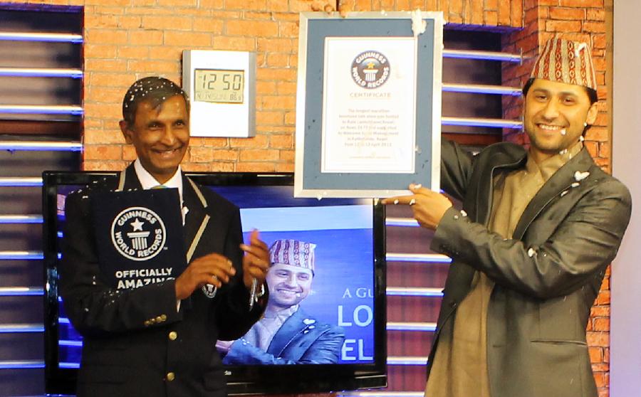Nepalese television presenter Rabi Lamichhane (R) is presented with a certificate by a Guinness World Records official after taking the world record for hosting longest television talk show in Kathmandu on April 14, 2013. Lamichhane set the world record for the longest television talk show by staying on air for 62 hours and 12 minutes, organisers said Sunday. One hundred guests, ranging from former Maoist rebel leader Pushpa Kamal Dahal, to the Indian ambassador to Nepal, to Nepalese television celebrities and common people joined Lamichhane during the programme. (Xinhua/AFP Photo)