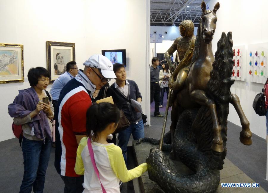 Visitors view a sculpture at the Art Beijing 2013 in Beijing, capital of China, May 1, 2013. Opened Wednesday at Agricultural Exhibition Center in Beijing, the annual art fair attracted some 150 participating art organizations. (Xinhua/Li Xin)