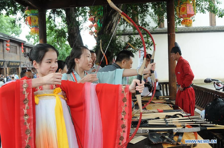 People wearing long robes of the archaic costumes typical of the Han Dynasty (202 BC - 221 AD) perform archery during a presentation event promoting the Han costumes and traditional etiquette in Fuzhou, capital of southeast China's Fujian Province, May 1, 2013. (Xinhua/Lin Shanchuan)