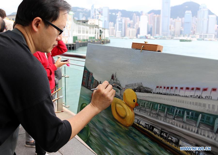 A painter draws the scene where a huge rubber duck floating on the waters at the Victoria Harbor in Hong Kong, south China, May 2, 2013. The largest rubber duck was created by Dutch artist Florentijn Hofman, with 18 meters of length, 15 meters of width and height. The duck has visited 12 cities since 2007. (Xinhua/Li Peng)