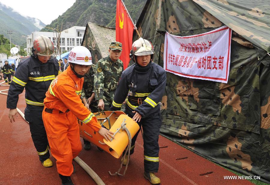 Fire fighters carry "an injured man" during a fire fighting drill held in a school playground in the quake-hit Baoxing County, southwest China's Sichuan Province, May 2, 2013. The school playground was served as the largest evacuation settlement for nearly 4,000 displaced people in Baoxing after the strong earthquake occurred in last month. (Xinhua/Lu Peng)