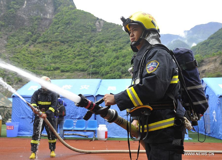 Fire fighters spray water during a fire fighting drill held in a school playground in the quake-hit Baoxing County, southwest China's Sichuan Province, May 2, 2013. The school playground was served as the largest evacuation settlement for nearly 4,000 displaced people in Baoxing after the strong earthquake occurred in last month. (Xinhua/Lu Peng)