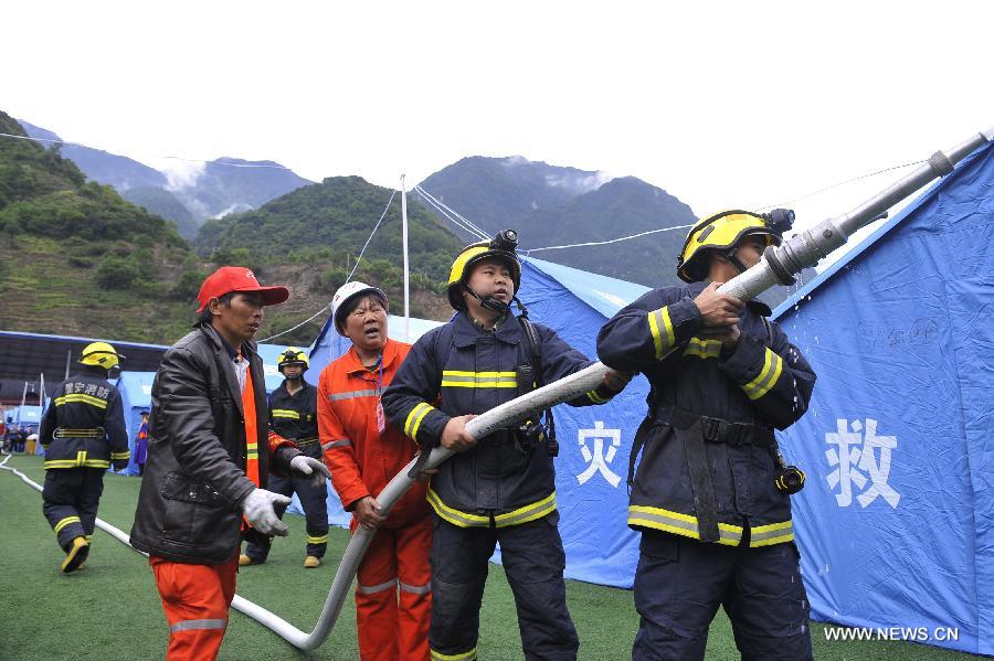 Fire fighters try to put out "a fire" during a fire fighting drill held in a school playground in the quake-hit Baoxing County, southwest China's Sichuan Province, May 2, 2013. The school playground was served as the largest evacuation settlement for nearly 4,000 displaced people in Baoxing after the strong earthquake occurred in last month. (Xinhua/Lu Peng)