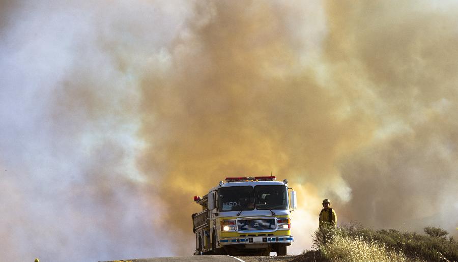 A fire fighter is seen near thick smoke near Malibu in California, the United States, May 3, 2013. The wind-driven wildfire forced the evacuation of a university campus and threatened some 4,000 homes in Southern California on Friday. (Xinhua/Yan Lei) 