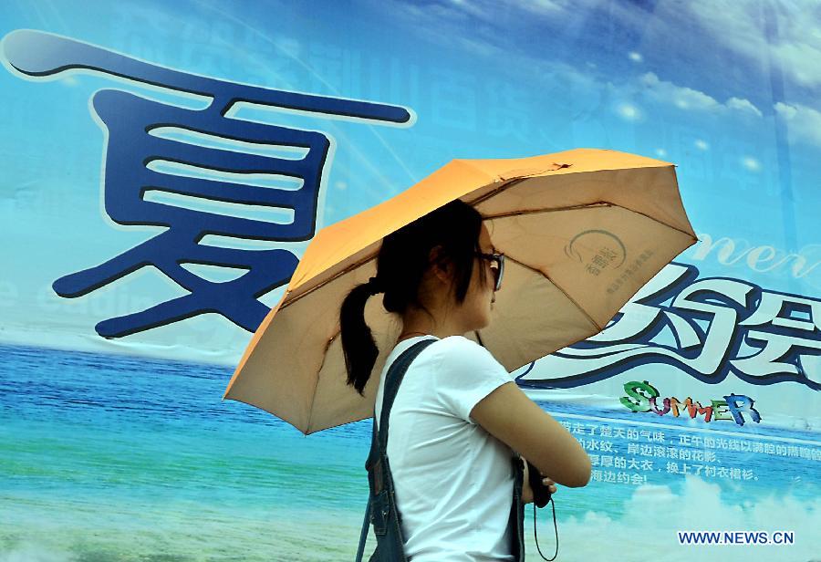 A woman wearing summer clothing walks past an advertisement board with the Chinese character meaning "summer" in Zhengzhou, capital of central China's Henan Province, May 5, 2013. Sunday is the beginning of the 7th solar term in Chinese lunar calendar, which indicates the coming of summer. The temperature in Henan rebounded in recent days. (Xinhua/Wang Song)