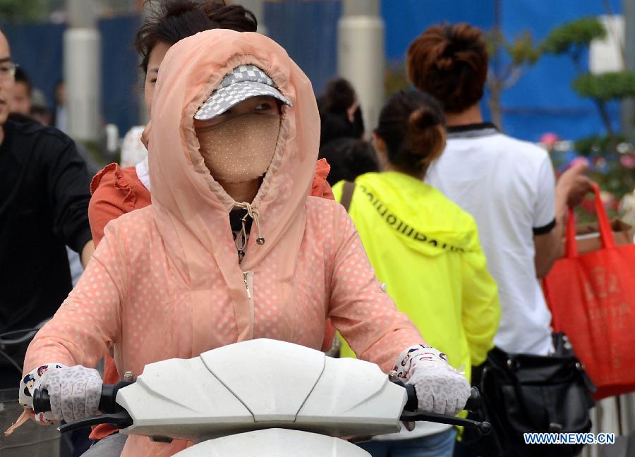 A woman wearing sun-protective clothing is seen riding in Zhengzhou, capital of central China's Henan Province, May 5, 2013. Sunday is the beginning of the 7th solar term in Chinese lunar calendar, which indicates the coming of summer. The temperature in Henan rebounded in recent days. (Xinhua/Wang Song)