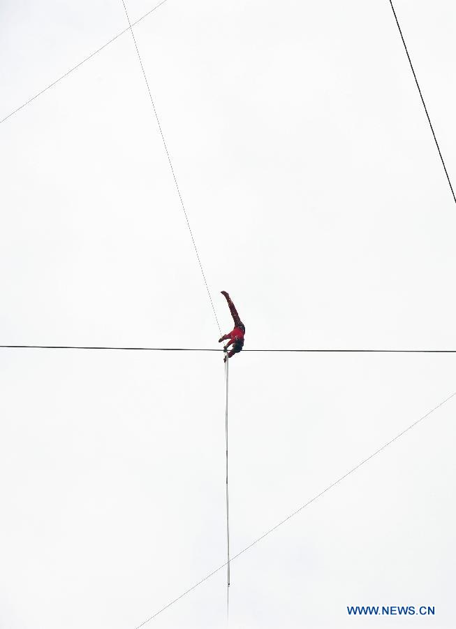 Tightrope walker Adili Wuxor, is balanced upside down on a steel wire that is 106-meters above the ground near Desheng River in Hangzhou, east China's Zhejiang Province, May 5, 2013. Adili successfully finished a series of performances here on Sunday. (Xinhua/Xu Hui)