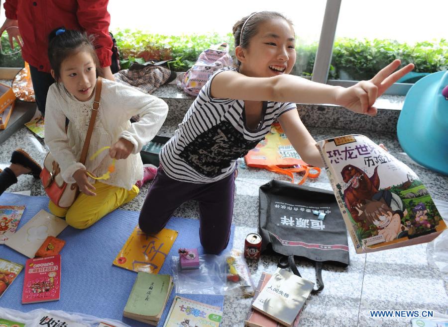 A girl sells her secondhand book at the secondhand book fair in Nanjing, capital of east China's Jiangsu Province, May 5, 2013. During the fair, pupils and middle school students could sell or exchange their idle books, stationery and toys as well, by which they were expected by the organizer to learn a frugal lifestyle. (Xinhua/Sun Can)