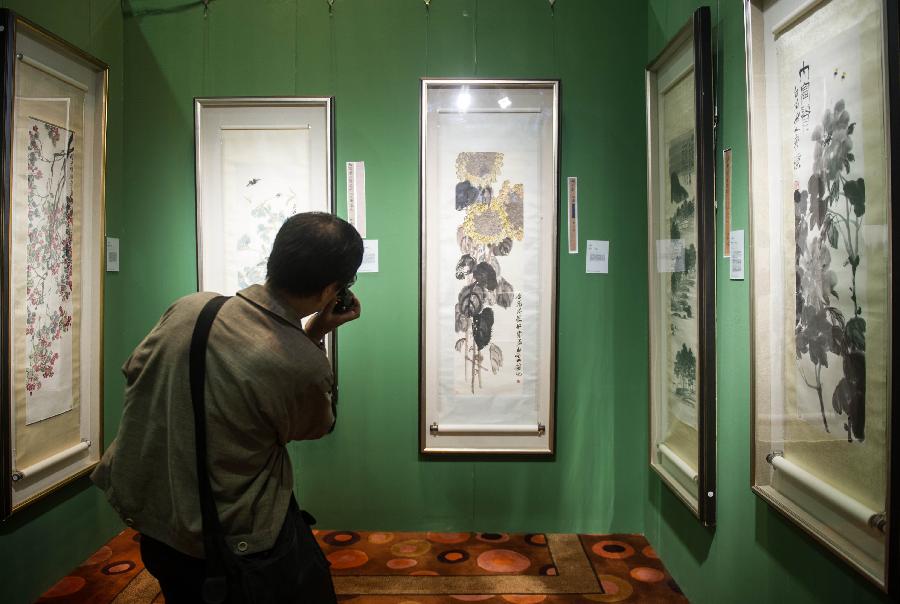 A visitor takes photos of a painting during the preview of China Guardian 2013 Spring Auctions in Beijing, capital of China, May 7, 2013. The three-day preview that opened on Tuesday displayed some 3,900 treasures to be auctioned on Friday. (Xinhua/Luo Xiaoguang) 