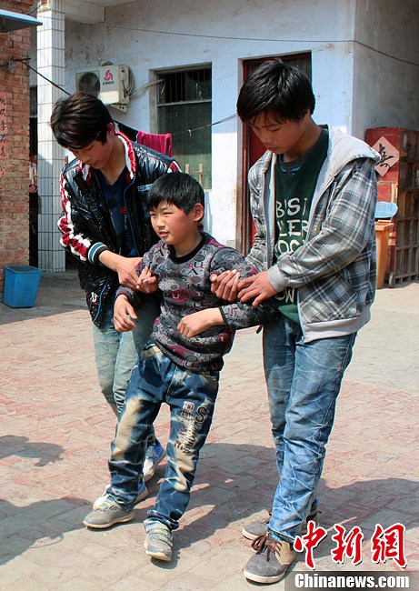 With the help of his classmates, Zongcheng practices walking every day. (CNS/Hu Ying)