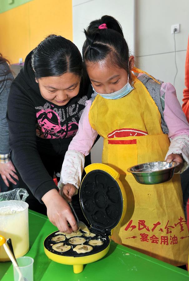 A girl named Hao Jinyue makes cakes with her mother in the Liyuejiayuan kindergarten in the Huaiyin District of Jinan, capital of east China's Shandong Province, May 10, 2013. Children here made cakes and helped make up for their mothers to celebrate the coming Mother's Day. (Xinhua/Zhu Zheng)  