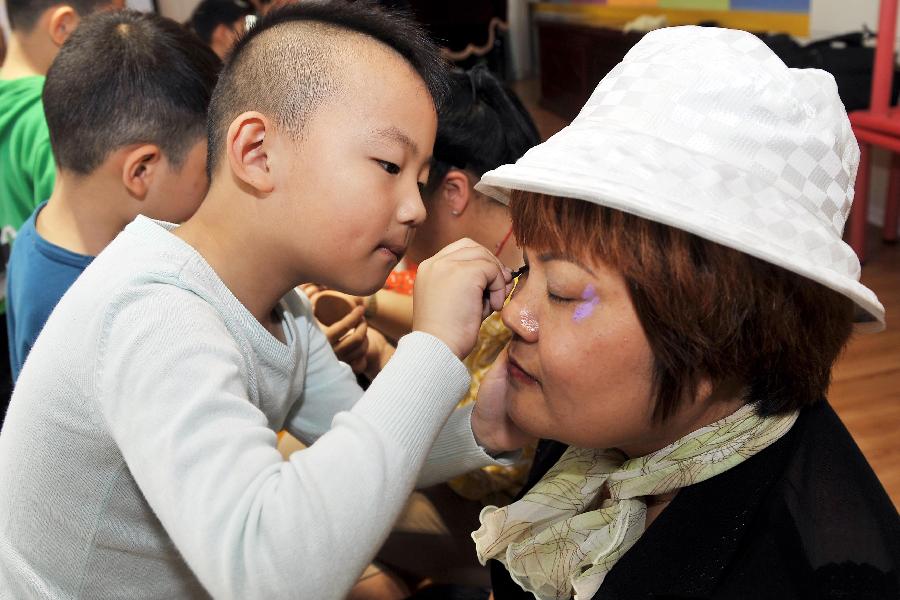 A boy named Pan Ziyang makes up for her mother in the Liyuejiayuan kindergarten in the Huaiyin District of Jinan, capital of east China's Shandong Province, May 10, 2013. Children here made cakes and helped make up for their mothers to celebrate the coming Mother's Day. (Xinhua/Zhu Zheng)