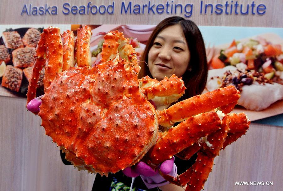 A woman tries to hold up a giant crab at the 15th International Exhibition of Food & Drink, Hotel, Restaurant & Food Service Equipment, Supplies & Services (HOFEX) in south China's Hong Kong, May 10, 2013. The four-day HOFEX 2013 kicked off on May 7 at Hong Kong Convention & Exhibition Center. (Xinhua/Chen Xiaowei) 