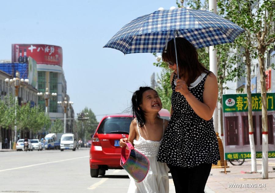 A mother and daughter walk with an umbrella in hand in Baoding City, north China's Hebei Province, May 11, 2013. A hot wave hit Hebei these days, with the highest temperature in parts of the province reaching 37 degrees Celsius. (Xinhua/Zhu Xudong)