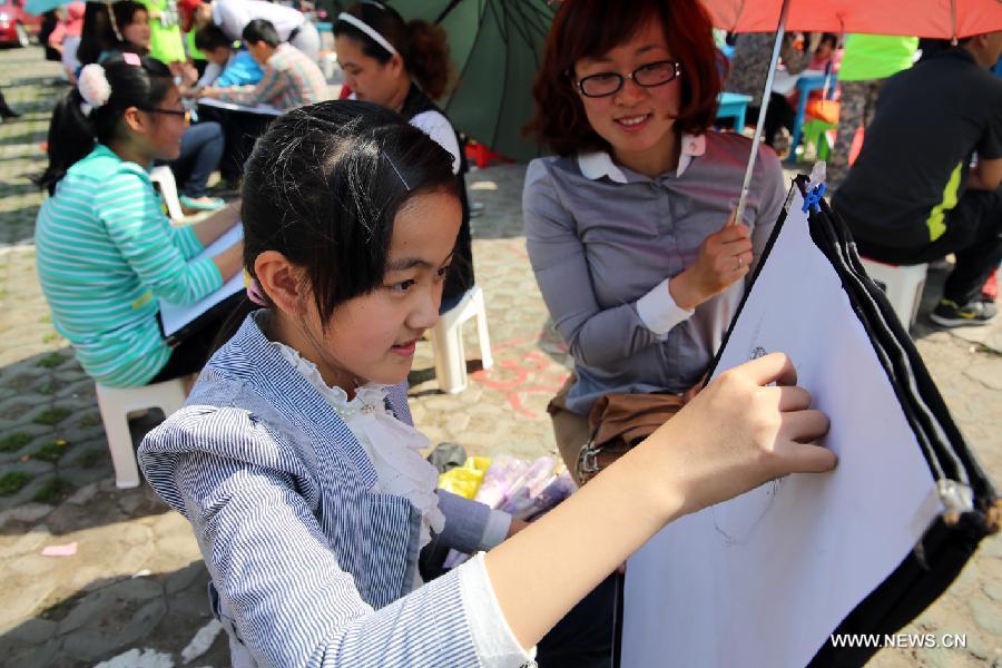 Children draw pictures of their mother during a celebration of the Mother's Day in Rizhao, east China's Shandong Province, May 12, 2013. (Xinhua/Hui Xueye)
