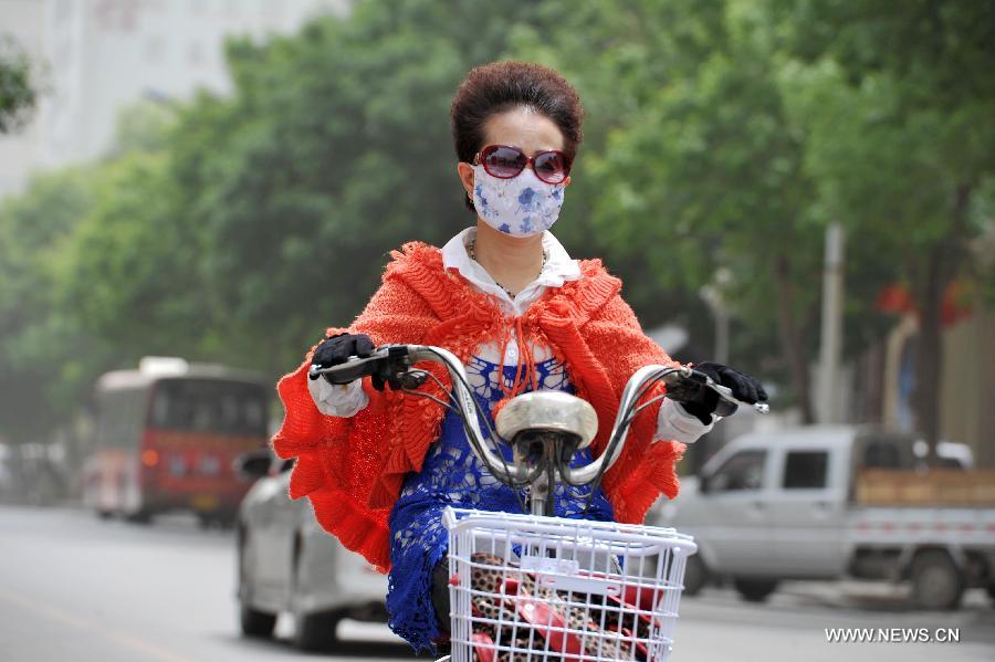 A woman covers her face with a scarf to protect her from floating dust in Yinchuan, capital of northwest China's Ningxia Hui Autonomous Region, May 13, 2013. Floating dust hit Yinchuan on Monday. (Xinhua/Peng Zhaozhi) 
