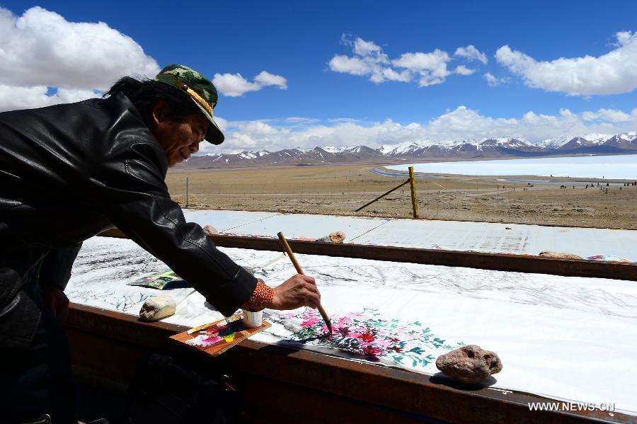 Painter Mo Huasheng draws a painting near the icy lake Nam Co located at the boundary of Damxung and Baingoin counties, southwest China's Tibet Autonomous Region, on May 12, 2013. Lake Nam Co, the highest saltwater lake of the world at 4,718 meters above the sea level, is regarded as a sacred lake in Tibetan Buddhism. (Xinhua/Chen Tianhu) 