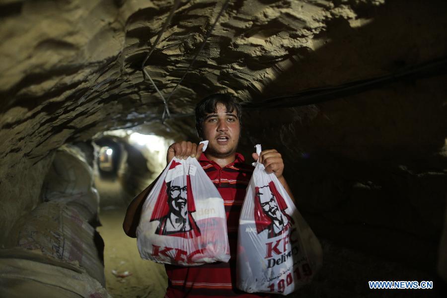 A man holds KFC food in the underground tunnel beneath the Gaza-Egypt border in the southern Gaza Strip city of Rafah on May 15, 2013. Ordering fast food from one of the world's most popular restaurants KFC has become possible in Gaza after Al-Yamama delivery company started to bring the food from the Egyptian north Sinai, which borders Gaza. (Xinhua/Wissam Nassar) 